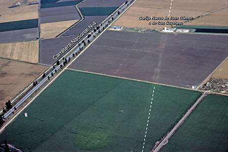 Foto aérea oblicua de las huellas de la vía Augusta que se dirige hacia el norte, en el cortijo nuevo de Juan Gómez o de San Calletano, en Utrera, con un trazado diferente de la carretera nacional N-4, visible arriba, a la izquierda (fotografía L. Ménanteau, 25-11-1978).