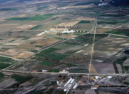 Foto aérea oblicua de la vía Augusta que se dirige hacia el sur con un trazado más rectilíneo que la carretera nacional 4, junto al cortijo Huerta de la Noria, al norte de los Palacios y Villafranca (fotografía L. Ménanteau, 25-11-1978)